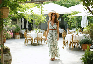Woman in a floral sundress and sunhat enjoying an outdoor garden restaurant with elegant table settings
