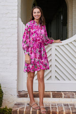 Rebecca Collared Tie Mini Dress in Pink Floral Ikat styled with flat sandals, showcasing a vibrant floral print for a breezy outdoor look.