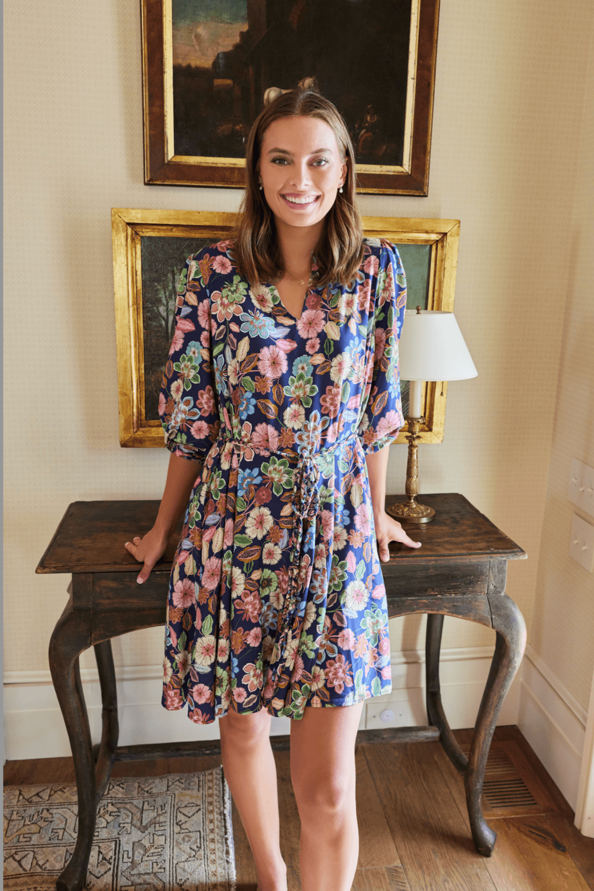 Gayle Belted Collard Mini Dress in Navy Floral with puff sleeves and V-neck, styled indoors with vintage decor. Elegant floral dress by Hermoza.