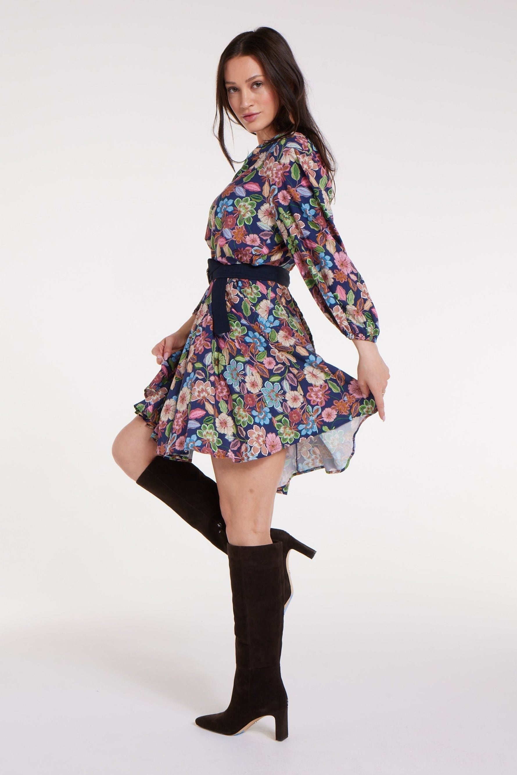 Side view of Gayle Belted Collard Mini Dress in Navy Floral with flared hem and navy belt, styled with heeled boots. Feminine floral dress by Hermoza.