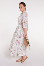 Side view of Francesca Collared Belted Maxi Dress in White Floral styled with straw hat and sandals, ideal for resort or vacation outfits.