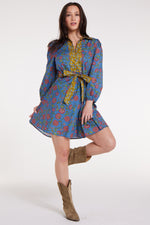 Model wearing Halle Collared Belted Mini Dress in Blue Floral with flared hem and yellow sash, styled with tan boots.